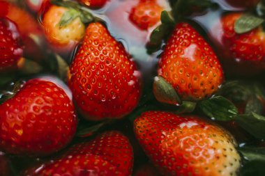 Beyaz bir mutfakta, gri bir mızrakta doğru temizlik için sırılsıklam olmuş çilekler..