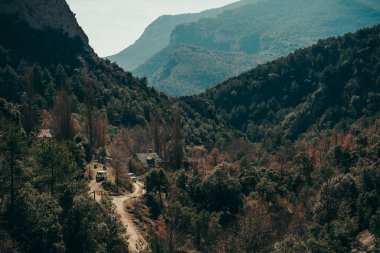Dağlık bir arazide gün batımı, ağaçlardan oluşan geniş bir orman..