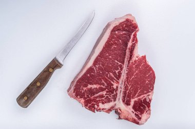 T-Bone bifteği, kasap masasında eski bir kemik bıçağının yanında kesilmiş.