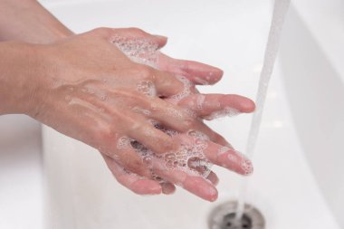Latin kadın evde ellerini sabunla yıkıyor.