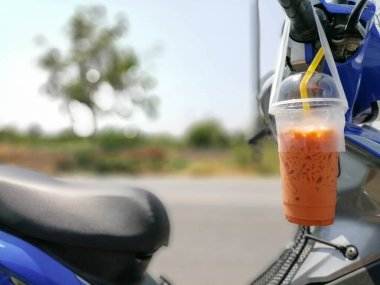 Thai milk tea is hanging at the motorcycle hand
