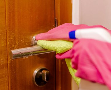 Eldiven ve bezle kapı kolunu temizliyorum.