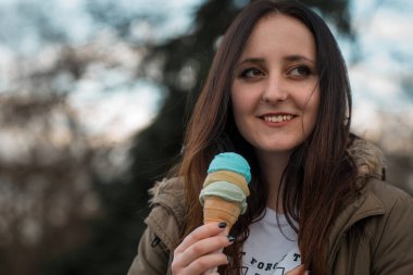 Güzel bir kız waffle külahında renkli bir dondurmayla dışarıda.