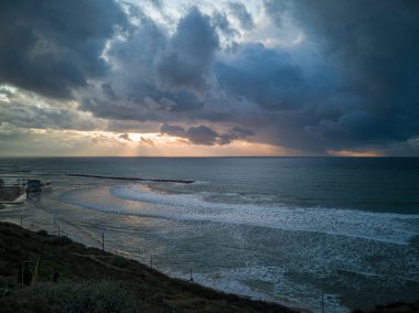 Netanya, İsrail 'de denizin üzerinde parlak güneş ışınlarıyla güzel bir gün batımı