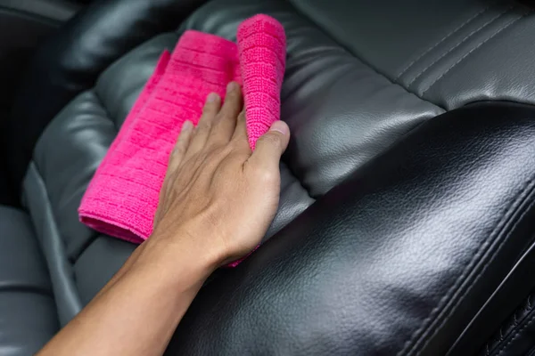 Bahçedeki pembe mikrofiber kumaşla araba koltuklarını temizleyen adam..