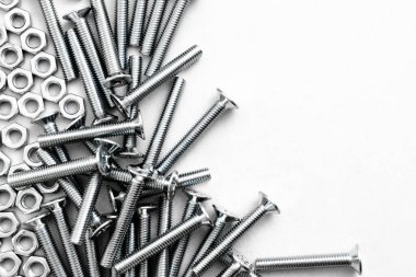 Paslanmaz çelik cıvataların ya da gümüş renkli parlak beyaz arka planda demir çivilerin üst görüntüsü. Metal vidalar metal levhada kullanılır.