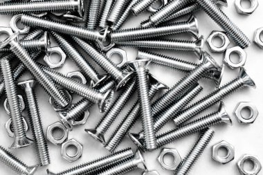 Paslanmaz çelik cıvataların ya da gümüş renkli parlak beyaz arka planda demir çivilerin üst görüntüsü. Metal vidalar metal levhada kullanılır.