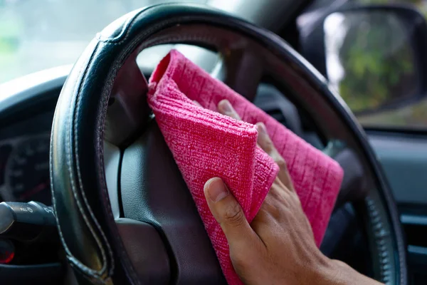 The man cleaning car with chemicals on pink microfiber cloth