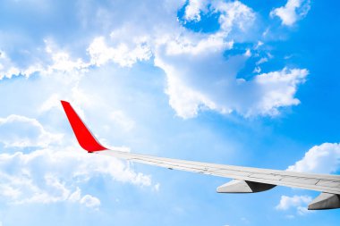 Pofuduk bulutlarla mavi gökyüzünde uçan bir uçağın kanadı. Tatil yolculuğuyla birlikte turizm ulaşımı. Metin veya web sitesi eklemek için iş ve seyahat kavramı.