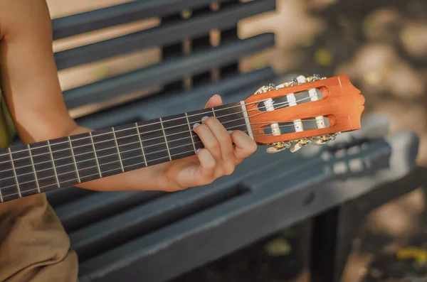 A boy wearing a face mask plays ukulele in front of a laptop Stock