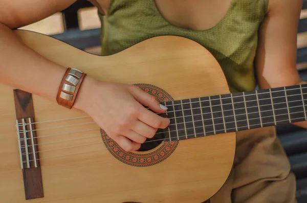 Kız ahşap gitar çalıyor. Kız gitarda melodi çalıyor.