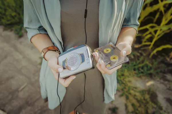 Genç bir kız elinde küçük bir kaset çalar ve elinde bir kaset tutuyor. Klasik kaset oynatıcı.