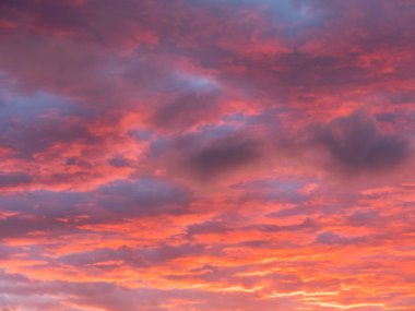Muhteşem kırmızı ve turuncu günbatımı bulutları mavi gökyüzüne karşı.