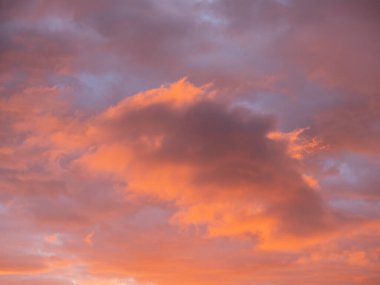 Muhteşem kırmızı ve turuncu günbatımı bulutları mavi gökyüzüne karşı.