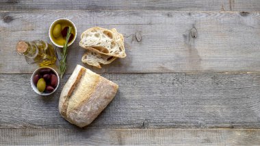Taze İtalyan ciabatta ekmeği otlar, zeytinyağı ve zeytinyağı eski ahşap masa, üst görünüm, düz yatıyordu.