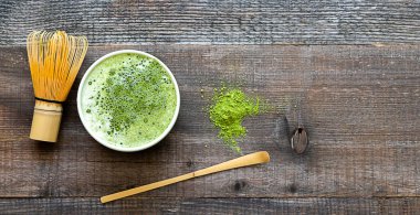 Yeşil kibrit latte içeceği ve çay aksesuarları ahşap masada fotokopi alanı ile 