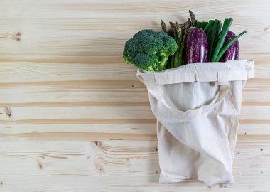 Sebzeli tekstil pamuk çanta. Sıfır atık. Ham ahşap arkaplan, kopyalama alanı.