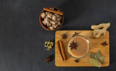 Geleneksel Hint masala çayı, içinde malzemeler olan cam bardakta..