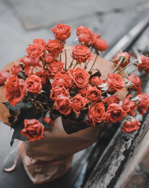 Kağıda sarılmış vazoda kırmızı güller.