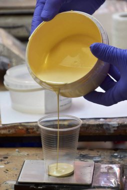 Ressam bir kabın içine boya döküyor.