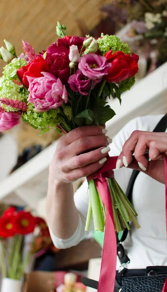 Florist shop in daylight. Woman holds a beautiful bouquet of flowers. Florist with her job.Small business.