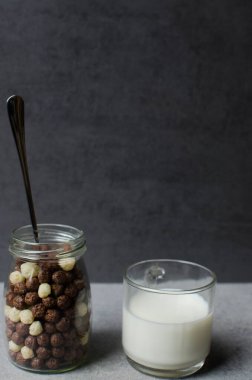 Gri bir zemine izole edilmiş çikolatalı mısır topları. Şeffaf ambalaj. Çiğ mısır gevreği. Şeffaf bir pakette gevrek. Spor kahvaltısı.