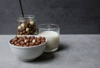 Gri bir zemine izole edilmiş çikolatalı mısır topları. Şeffaf ambalaj. Çiğ mısır gevreği. Şeffaf bir pakette gevrek. Spor kahvaltısı.