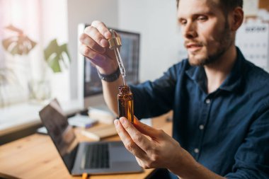 Vitaminler ve takviyeler. El ele tutuşan kenevir yağı. Yakından adam CBD yağı kullanıyor. Tıbbi kenevir. Sağlıklı yaşam tarzı