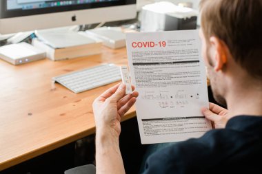 Riga, Letonya - 8 Nisan 2020: Coronavirus SARS-CoV-2 evde test ediliyor. COVID-19 Coronavirus için hızlı test kaseti. Hızlı test kiti tutan bir adam. Kılavuzu okuyan adam evde nasıl test yapılacağını biliyor.