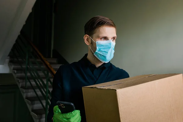 Grocery delivery man wearing medical gloves and face mask. Online shopping and delivery for groceries, wine and food. Self Quarantine during coronavirus pandemic. Food delivery service courier