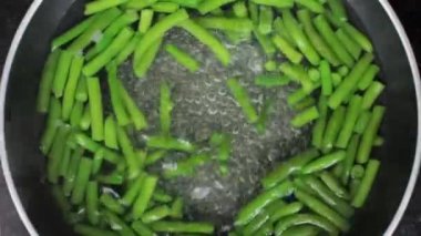 Yeşil fasulyeler tavada kaynatılır. Su kaynıyor.