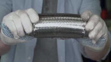 Eldivenli eller arabanın egzoz sistemini tutar.