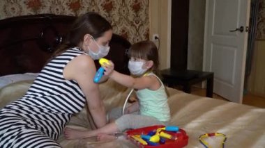 Anne ve bebek evde tıbbi maskelerle oynuyor. Kendini izole etmeyi karantinaya alıyorlar.