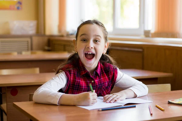 教室の机の上に座っている笑顔の白人女の子は喜んで叫ぶ 女子高生の肖像画 幸せな弟子 — ストック写真
