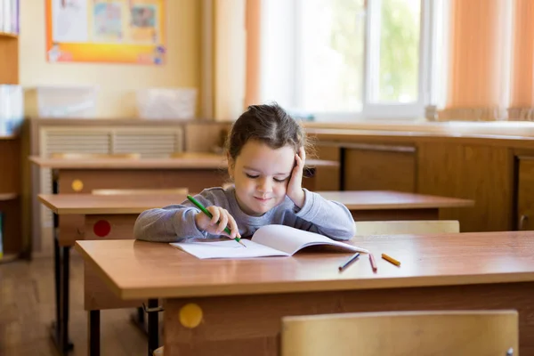 教室の机に腰を下ろしていた白人の少女は純然たるノートに丁寧に描き始める 幸せな弟子 — ストック写真