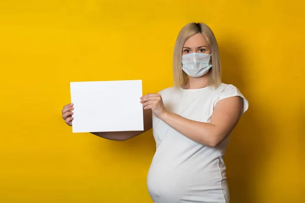 Een Zwangere Vrouw Met Een Beschermend Masker Houdt Een Blanco — Stockfoto