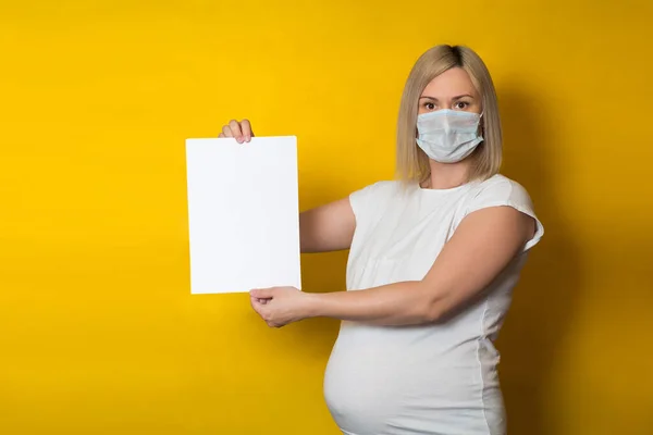 Een Zwangere Vrouw Met Een Beschermend Masker Houdt Een Blanco — Stockfoto