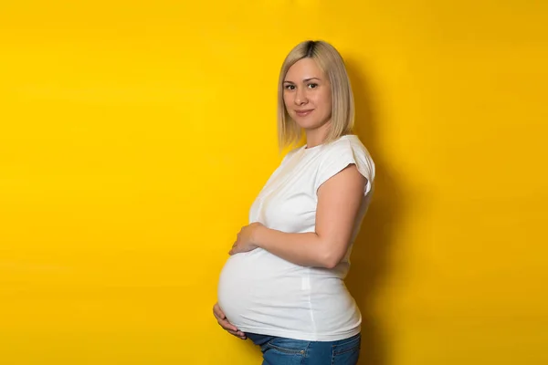 Een Vrolijke Zwangere Vrouw Een Wit Shirt Jeans Staat Zijdelings — Stockfoto