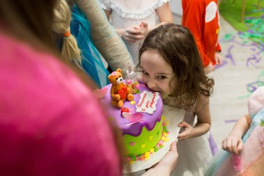 Küçük bir kız altı yıl onuruna güzel bir pastayı ısırır. Pastadaki yazı Pauline, doğum günün kutlu olsun..