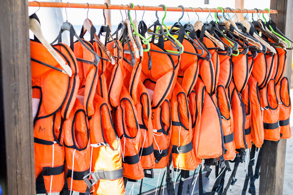 lots of orange life jackets hanging on hangers