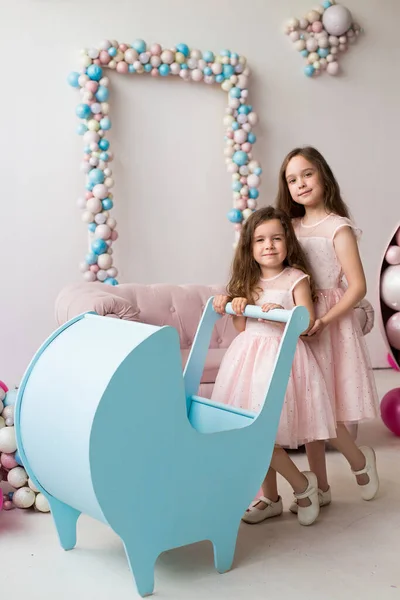 Kleine Meisjes Roze Jurken Spelen Met Een Blauwe Kinderwagen Als Rechtenvrije Stockfoto's