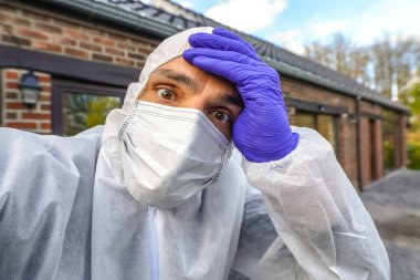 Dünya çapında Coronavirus salgını sırasında antiviral koruyucu yüz maskesi ve tulumu takan doktor Avrupa, ABD ve Çin 'de kilit altında. Tehlikeli SARS-CoV-2 virüs salgını.