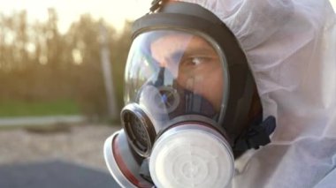 Dünya çapında Coronavirus covid-19 SARS-CoV-2 salgını sırasında solunum maskesi ve beyaz tehlikeli madde önlüğü takan ve mavi eldiven giyen bir adam..