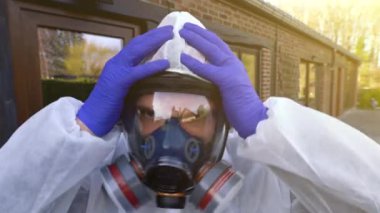 Dünya çapında Coronavirus covid-19 SARS-CoV-2 salgını sırasında solunum maskesi ve beyaz tehlikeli madde maskesi takan bir adam..