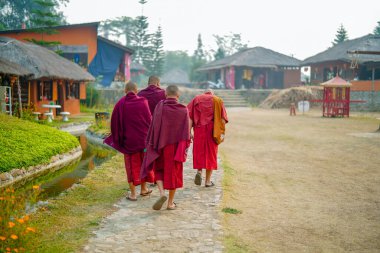 Pai, Tayland - 23 Mart 2019: Çin Budist rahipleri beline kırmızı bornozla bağlanmış huzur dolu bir Çin Kültür Köyünde yürüyorlar.