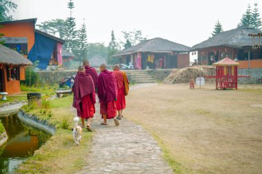 Pai, Tayland - 23 Mart 2019: Çin Budist rahipleri beline kırmızı bornozla bağlanmış huzur dolu bir Çin Kültür Köyünde yürüyorlar.