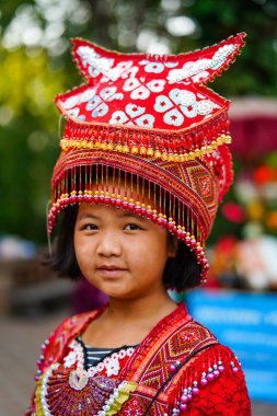 Chiang Mai, Tayland - 21 Mart 2019 Wat Phrathat tapınağının merdivenlerinde, Tayland 'ın başkenti Chiang Mai' de Doi Suthep Dağları 'nda geleneksel kırmızı elbise ve şapka giyen gülümseyen Hmong kabilesi kızı