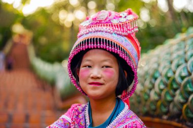 Chiang Mai, Tayland - 21 Mart 2019 Wat Phrathat tapınağının merdivenlerinde, Tayland 'ın başkenti Chiang Mai' de Doi Suthep dağlarında geleneksel pembe elbiseler ve şapkalar giyen gülümseyen Hmong kabilesi kızı