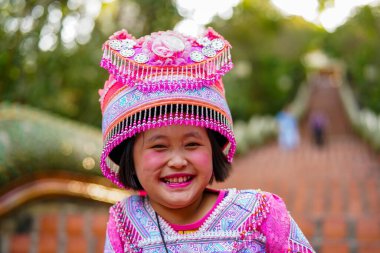 Chiang Mai, Tayland - 21 Mart 2019 Wat Phrathat tapınağının merdivenlerinde, Tayland 'ın başkenti Chiang Mai' de Doi Suthep dağlarında geleneksel pembe elbiseler ve şapkalar giyen gülümseyen Hmong kabilesi kızı