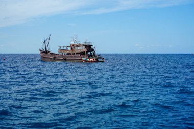 Güneşli bir günde denizde yüzen eski bir tekne